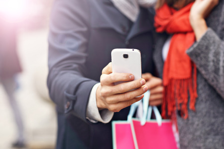 Midsection of young couple shopping in the city with smartphoneの写真素材