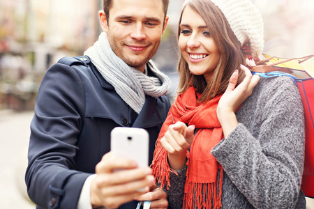 Young couple shopping in the city with smartphoneの写真素材