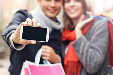 Midsection of young couple shopping in the city with smartphoneの写真素材