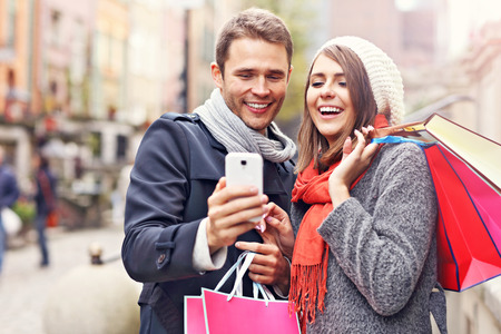Young couple shopping in the city with smartphoneの写真素材