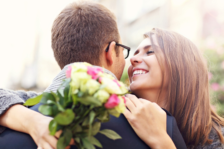 Picture showing happy couple hugging with flowers in the cityの写真素材