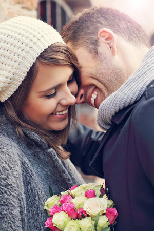 Picture showing happy couple hugging with flowers in the cityの写真素材