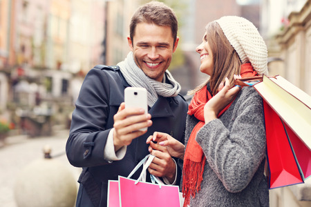 Young couple shopping in the city with smartphoneの写真素材