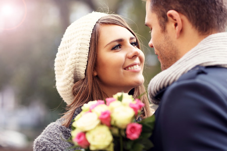 Picture showing happy couple hugging with flowers in the cityの写真素材