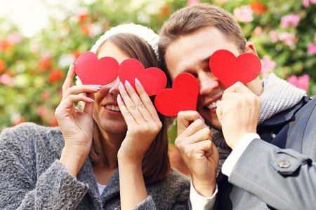 Picture of happy couple covering eyes with heartsの写真素材