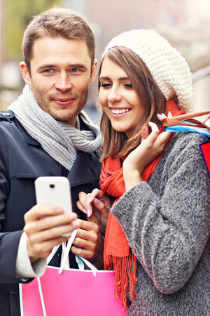 Young couple shopping in the city with smartphoneの写真素材