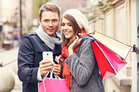 Young couple shopping in the city with smartphoneの写真素材