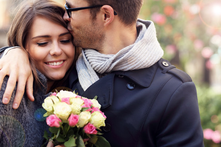 Picture showing happy couple hugging with flowers in the cityの写真素材
