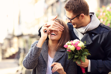 Picture of young man surprising woman with flowersの写真素材