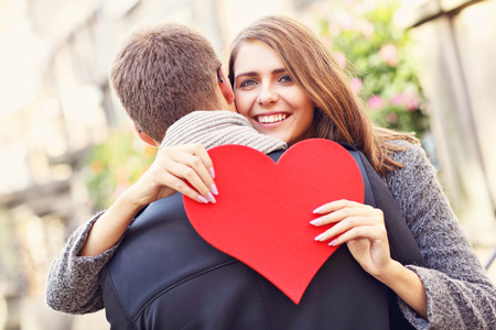 Picture showing happy couple hugging with flowers and heart in the cityの写真素材