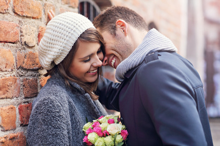 Picture showing happy couple hugging with flowers in the cityの写真素材