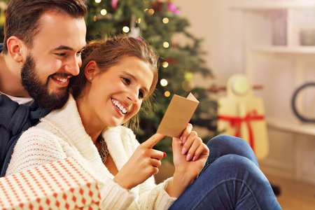Picture showing young couple with present over Christmas treeの写真素材