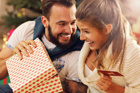Picture showing young couple with present over Christmas treeの写真素材