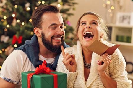 Picture showing young couple with present over Christmas treeの写真素材