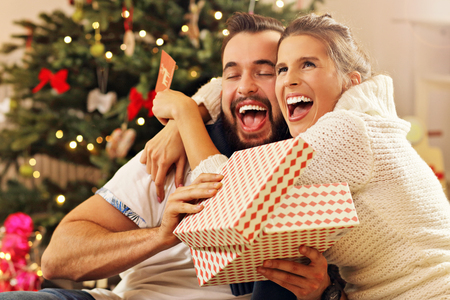 Picture showing young couple with present over Christmas treeの写真素材