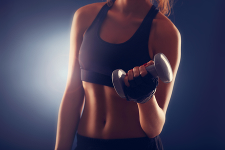 Midsection of woman lifting dumbellsの写真素材