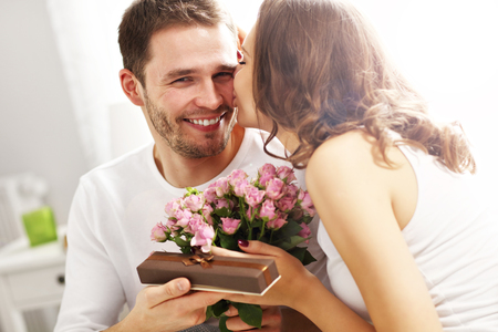 Picture showing man giving flowers and present to woman in bedの写真素材
