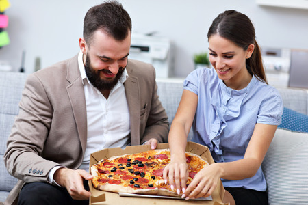Picture showing businesspeople eating pizza in officeの写真素材
