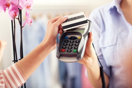 Closeup mid section of female customer paying in shop with credit cardの写真素材