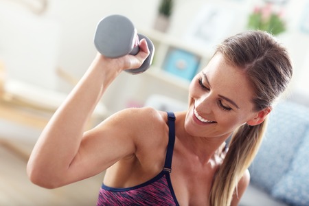 Woman exercising with dumbbells at homeの写真素材