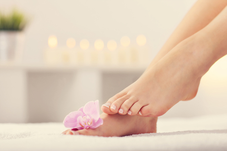 Soft female feet with french pedicure and flowers close upの写真素材