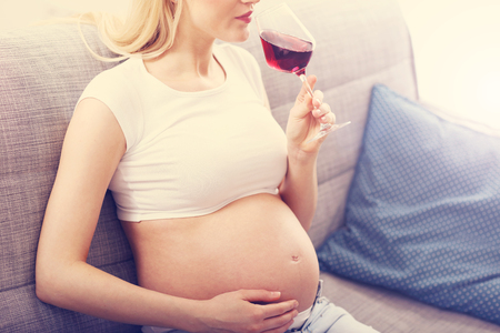 Close up of pregnant woman with glass of wineの写真素材