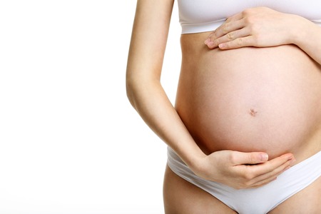 Picture of pregnant woman showing her belly over white backgroundの写真素材