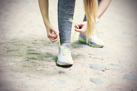 Woman jogging in the forest and tying shoeの写真素材