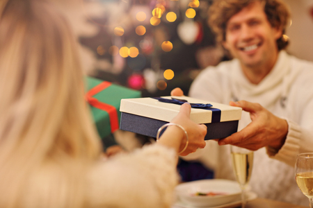 Group of friends giving Christmas presents at homeの写真素材