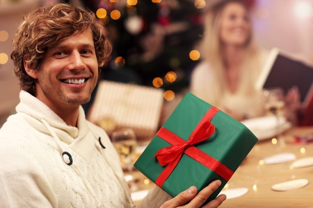 Group of friends giving Christmas presents at homeの写真素材
