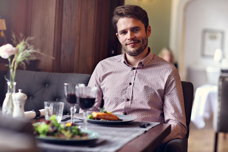 Handsome man waiting at table in restaurantの写真素材