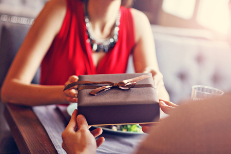 Midsection of romantic couple dating in restaurant and having presentの写真素材