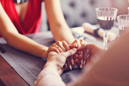 Couple eating romantic Dinner in a gourmet restaurant drinking wine and holding handsの写真素材