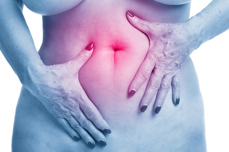Senior woman touching abdomen over white backgroundの写真素材