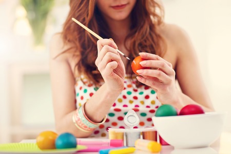 Attractive woman painting Easter eggs at homeの写真素材