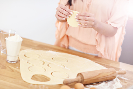 Young woman trying to make pierogi in kitchenの写真素材