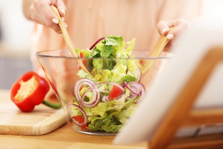 Happy woman preparing salad in modern kitchenの写真素材