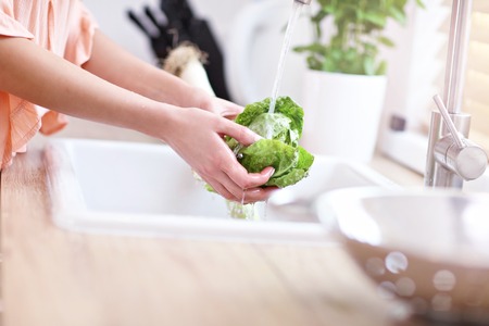 Young woman washing lettuce in modern kitchenの写真素材
