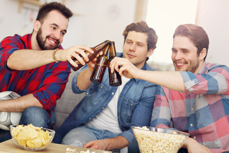 Happy male friends cheering and watching sports on tvの写真素材