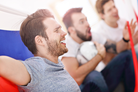 Happy male friends cheering and watching sports on tv