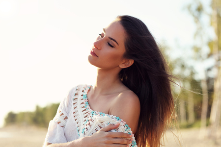 Beautiful calm woman at dusk on the beachの写真素材