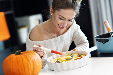 Adult woman in the kitchen preparing pumpkin dishes for Halloweenの写真素材