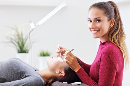 Adult woman having eyelash extension in professional beauty salonの写真素材