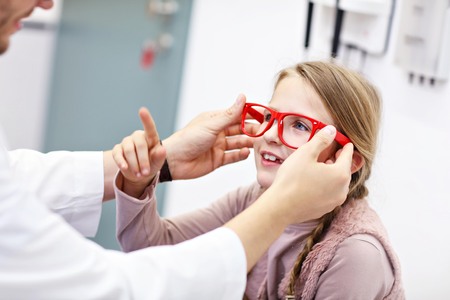 Child male optometrist examines eyesight of little girl