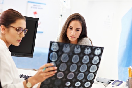 Adult woman discussing x-ray results during visit at female doctors officeの写真素材