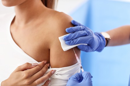 Adult woman having injection during visit at female doctors officeの写真素材