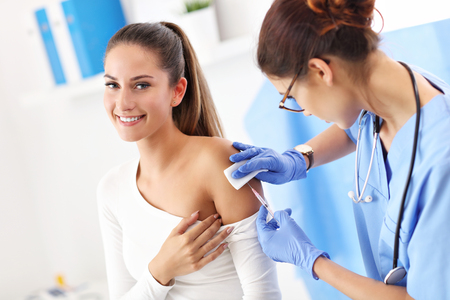 Adult woman having injection during visit at female doctors officeの写真素材