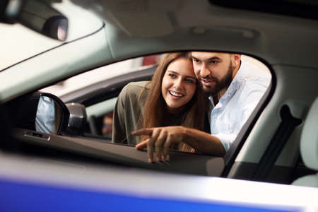 Adult couple choosing new car in showroomの写真素材