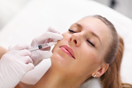 Close up of hands of cosmetologist making  injection in female lipsの写真素材