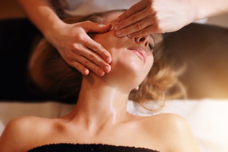 Happy woman having face massage in spa salonの写真素材